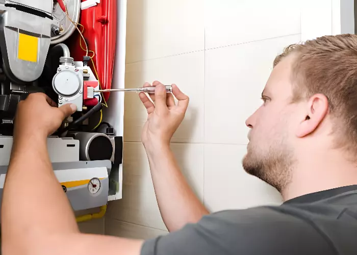 A technician repairs a tankless water heater with a screwdriver.
