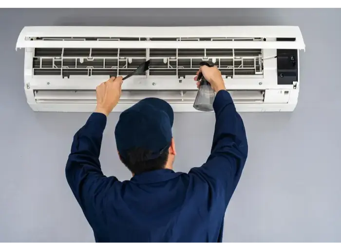 Person cleaning an air conditioner.