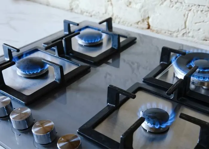 A gas stove with four burners and blue flames.