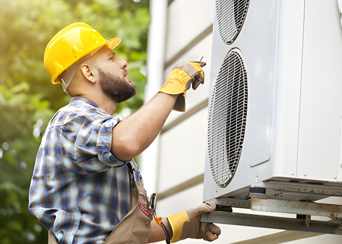 An HVAC technician is installing an air conditioner on the exterior of a building.