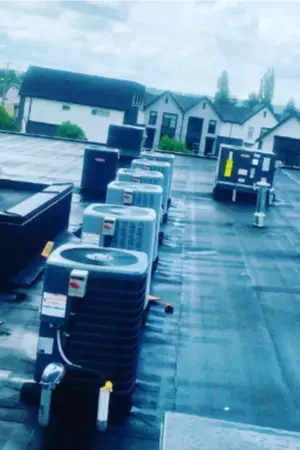 A row of air conditioners sits on a flat roof.