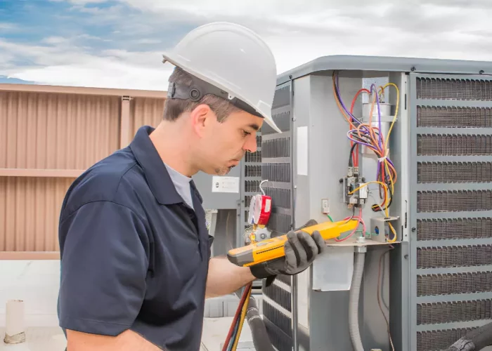 Technician performing AC maintenance with a multimeter.